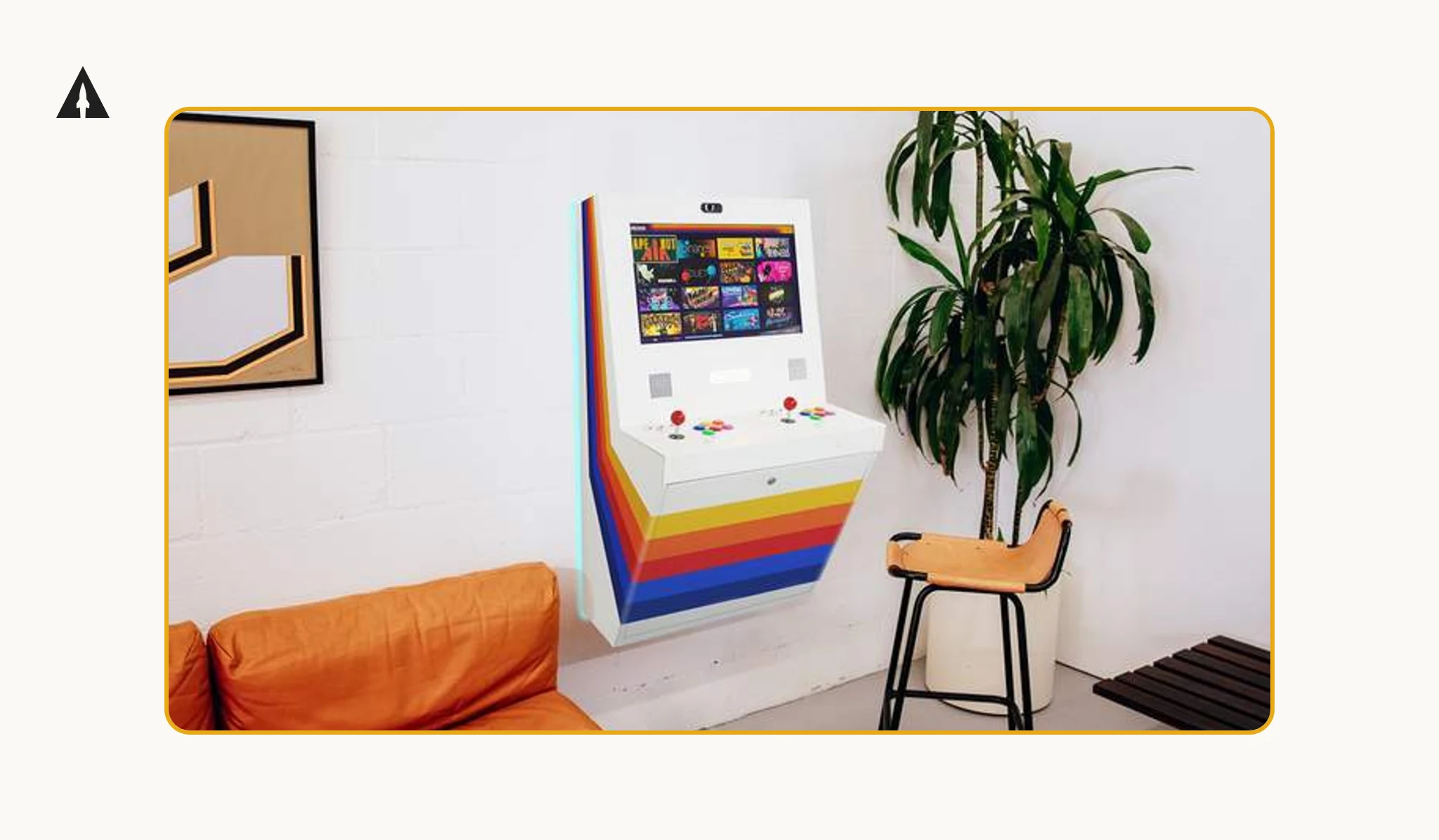 A white wall-mounted arcade machine with rainbow stripes, next to a potted plant and a bar stool