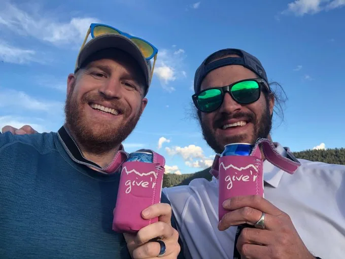 Two Give'r founders holding pink Give'r koozies