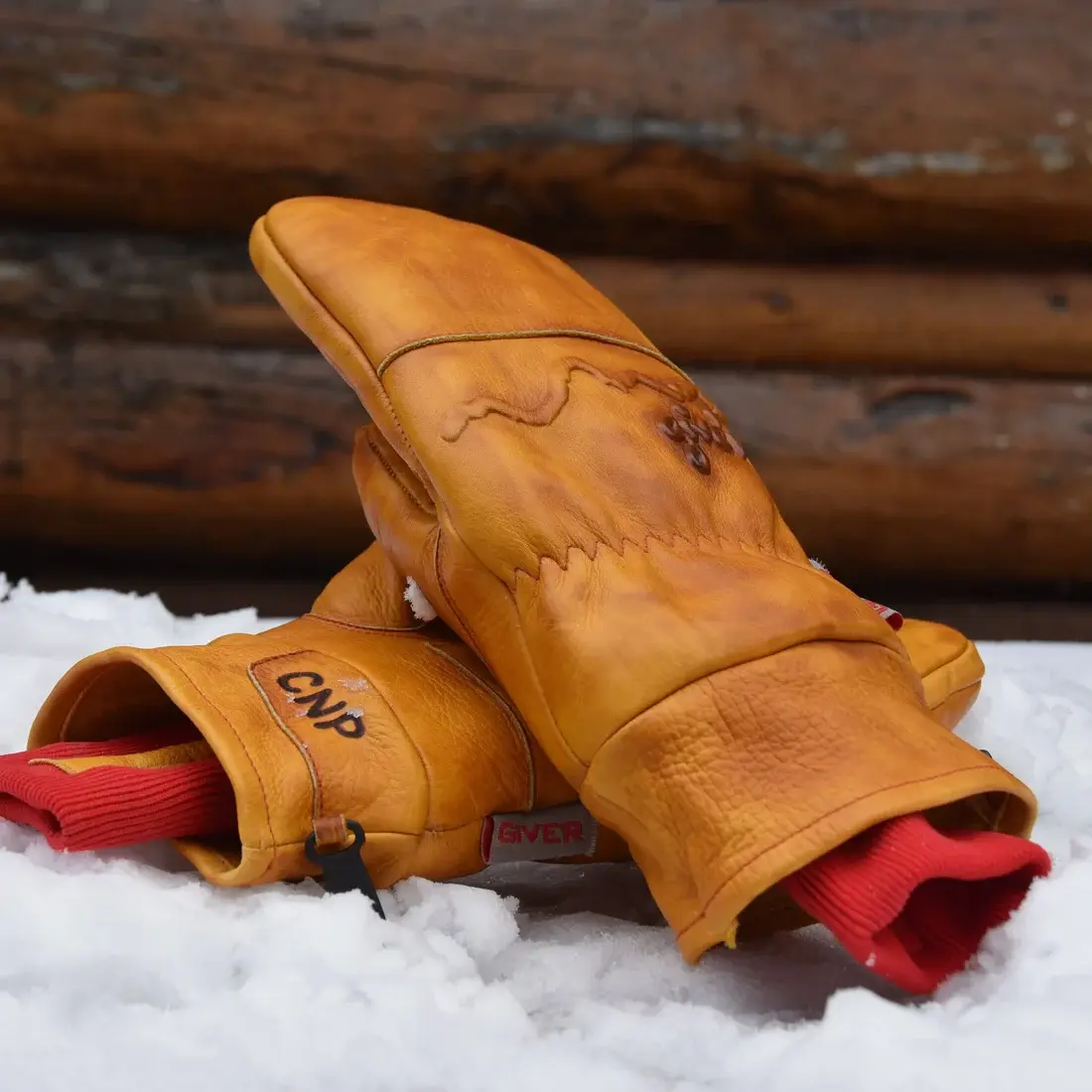A pair of leather Give'r mittens resting in the snow