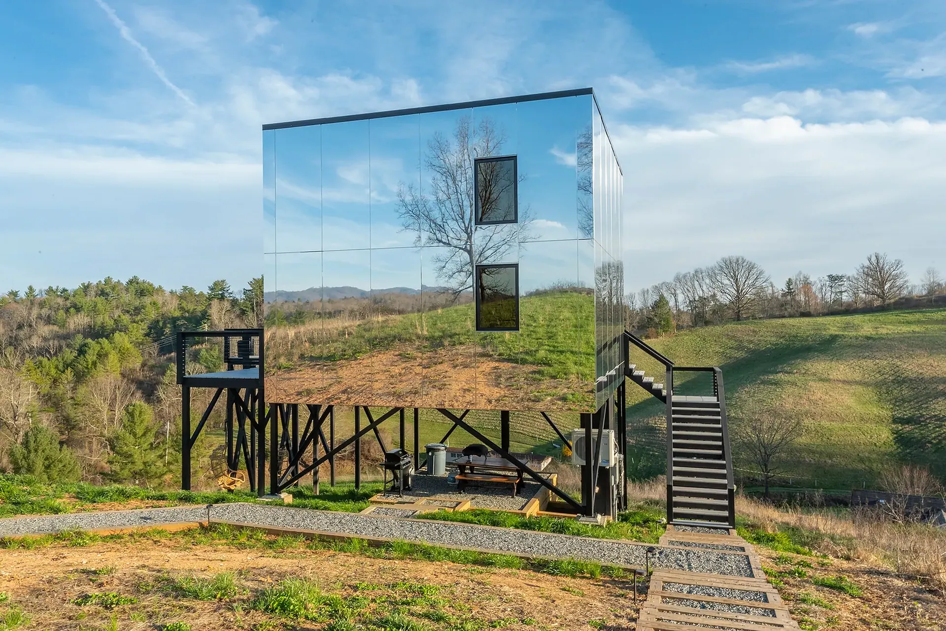A mirror-clad Mirror Hotel cabin reflecting the surrounding fields and sky