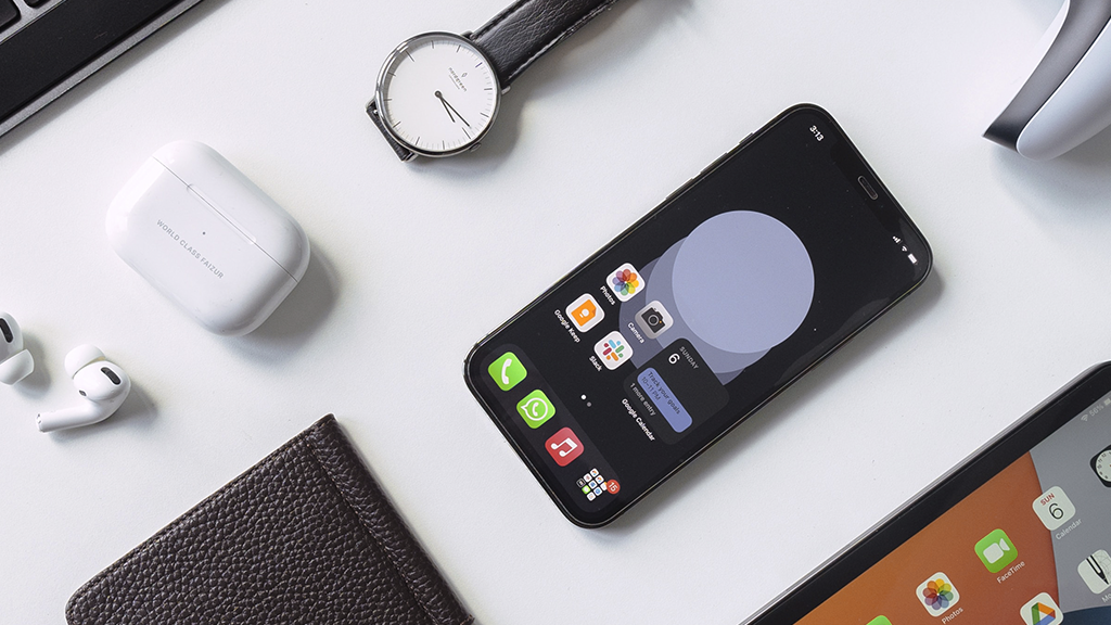 A smart phone, a watch, and various phone accessories are laid out on a white surface.